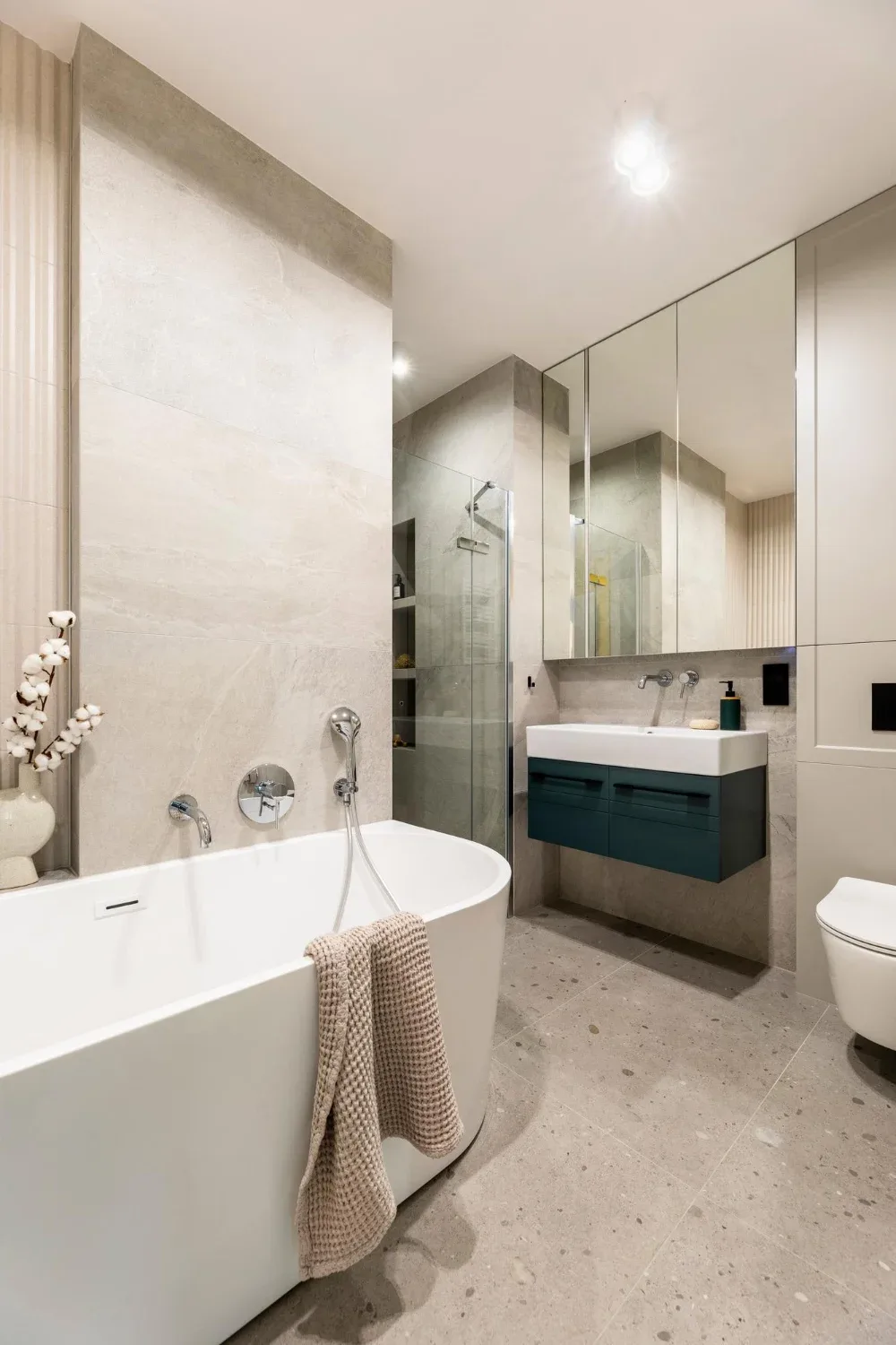 Badkamer met grote natuursteenlook wandtegels, vrijstaand bad en inloopdouche