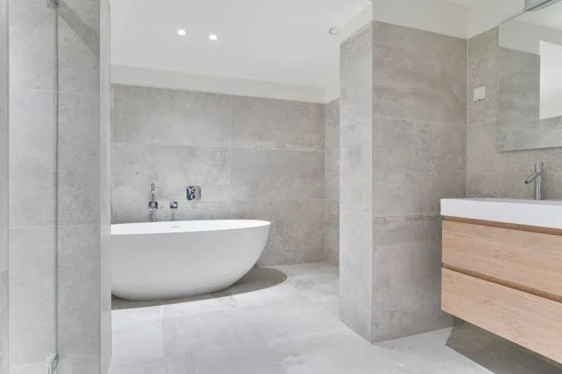 Moderne badkamer in Utrecht met grootformaat grijze tegels en vrijstaand bad